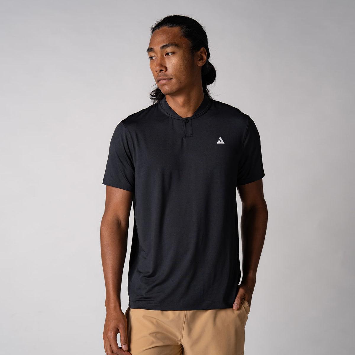 Mann trägt schwarzes, kurzärmeliges Sportshirt mit kleinem weißem Logo auf der Brust vor hellem Hintergrund.