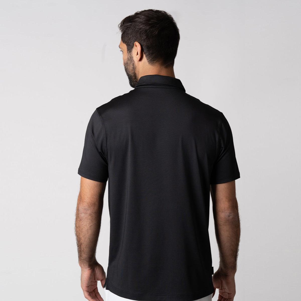 Mann von hinten trägt schwarzes, kurzärmeliges Poloshirt vor hellem Hintergrund.