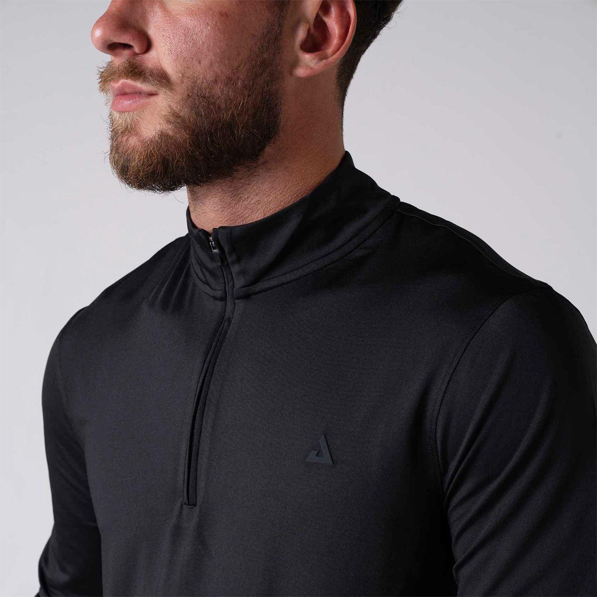 Mann trägt schwarzes Langarmshirt mit halbem Reißverschluss und kleinem Logo auf der Brust.