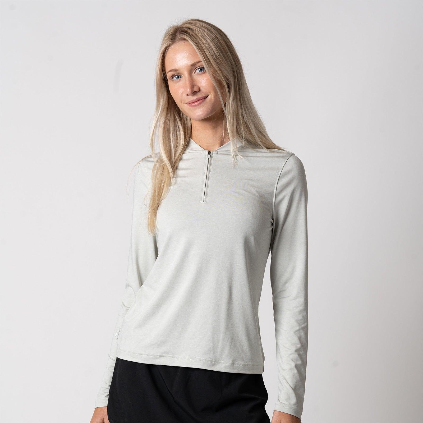 Frau trägt langärmeliges, hellgraues Sportshirt mit kurzem Reißverschluss.