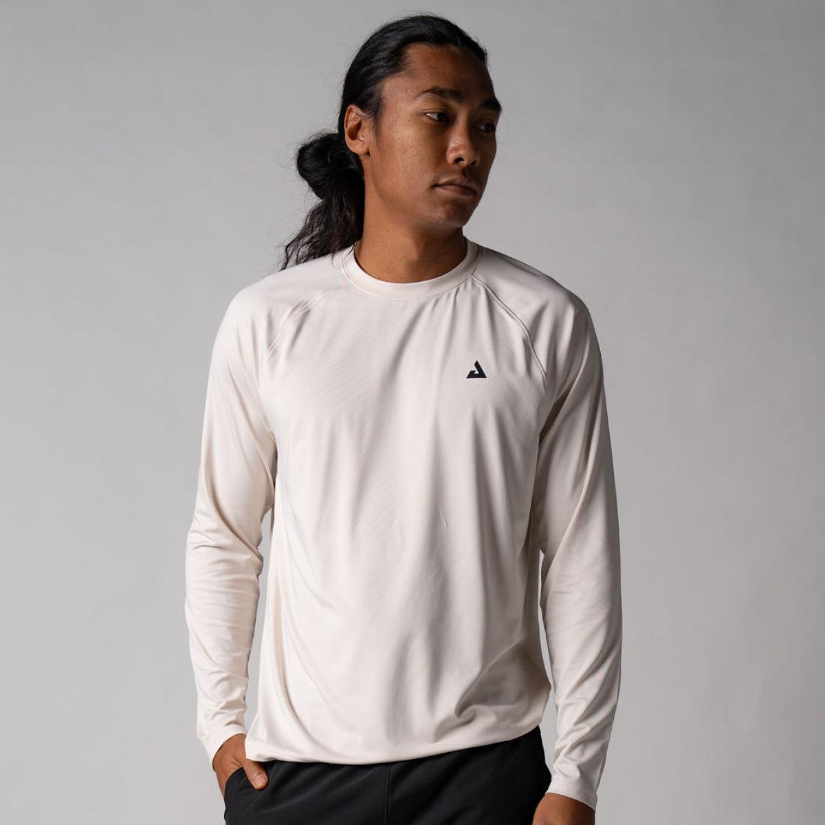 Mann trägt hellbeiges, langärmliges Sportshirt mit kleinem schwarzem Logo auf der Brust.