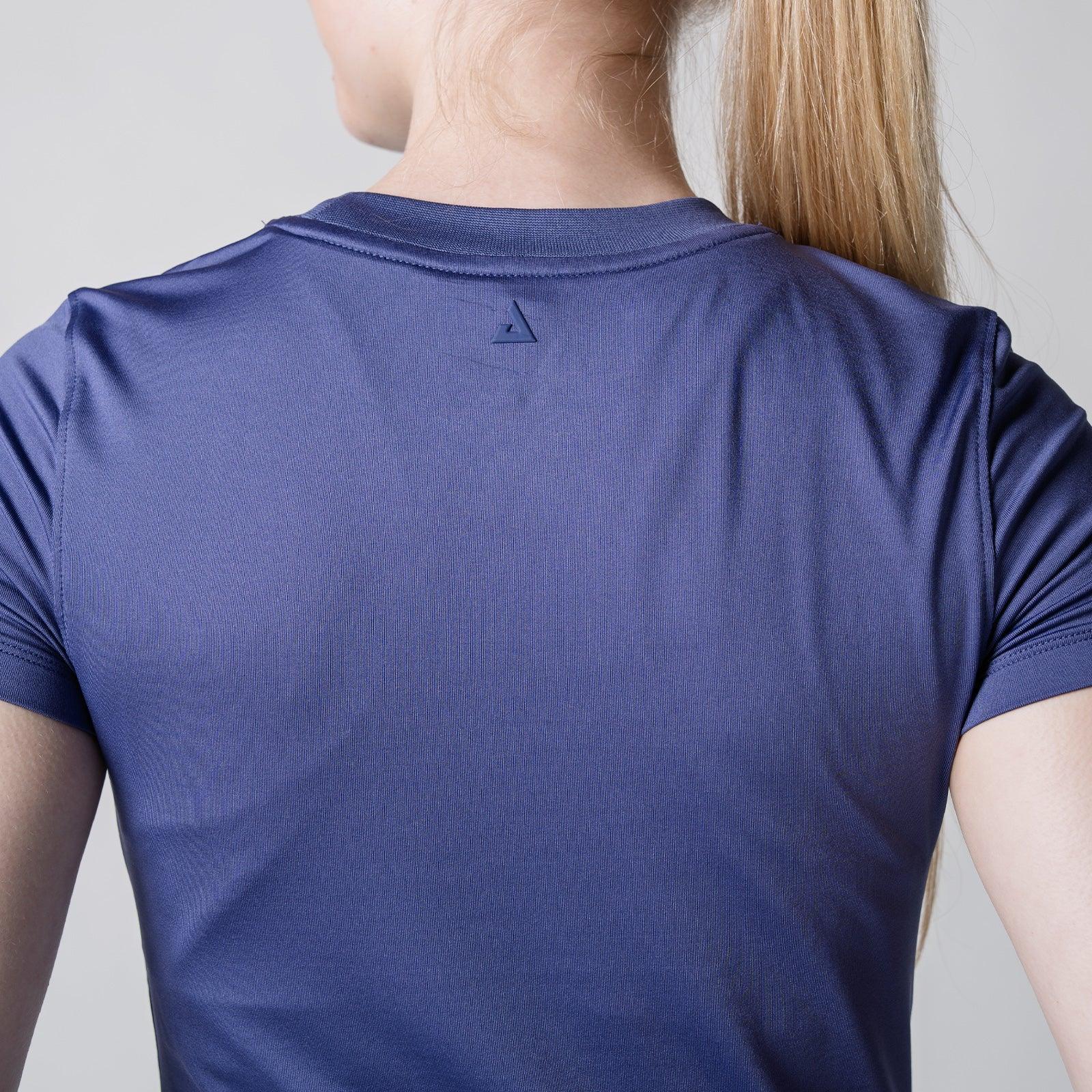 Rückansicht eines dunkelblauen, kurzärmligen Sportshirts aus atmungsaktivem Material, getragen von einer Person mit blondem Pferdeschwanz.