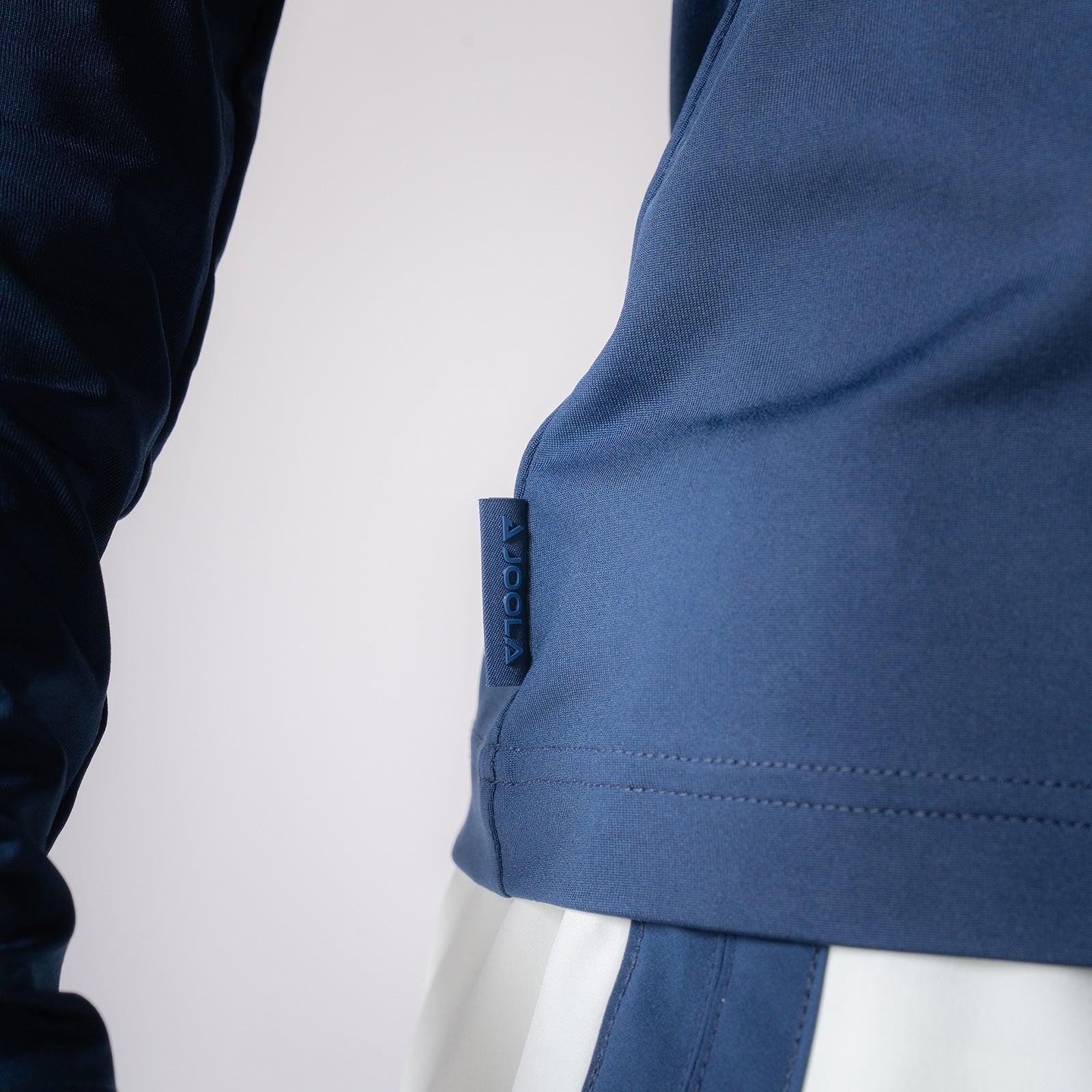 Nahaufnahme eines blauen Sportshirts mit sichtbarem JOOLA-Logo am Saum.