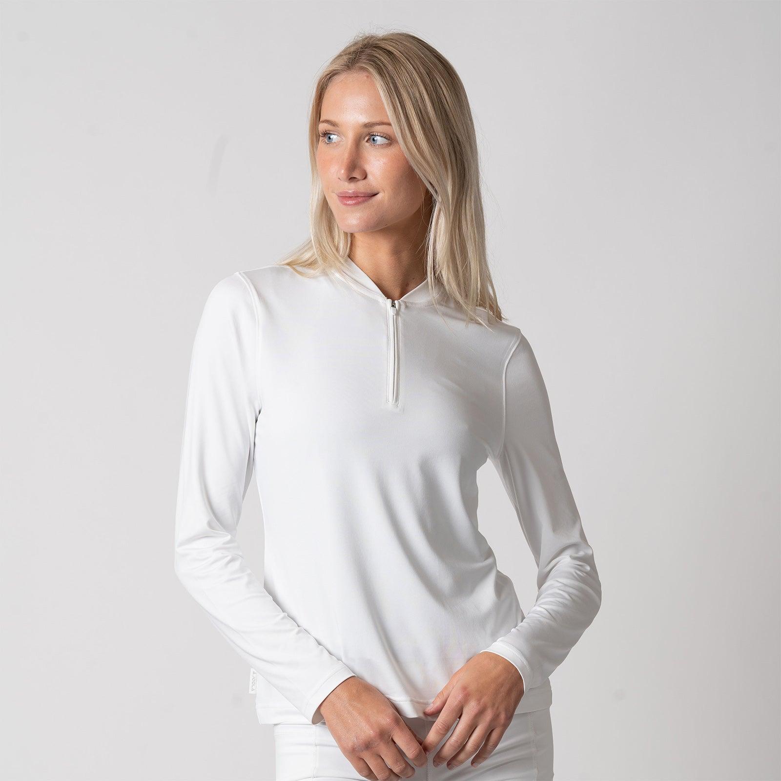 Frau trägt weißes, langärmliges Shirt mit kurzem Reißverschluss am Kragen vor hellem Hintergrund.