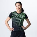 Frau trägt schwarzes Sportshirt mit grünem, geometrischem Muster und kurzem Ärmel vor weißem Hintergrund.