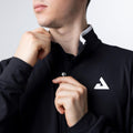 Mann zieht schwarzen Sportpullover mit Reißverschluss und weißem Logo am Brustbereich hoch.